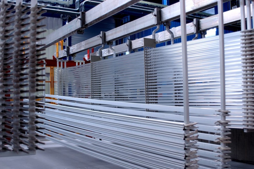 Profili di alluminio disposti su bilancelle all'interno di un impianto di anodizzazione.